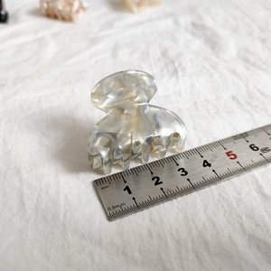 Macro detail of a 4cm small marble pattern hair claw clip with acetate finish and metal ruler