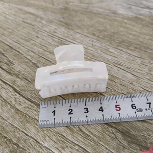 Vue détaillée d'une pince à cheveux de 4,5 cm en acétate blanc nacré sur bois