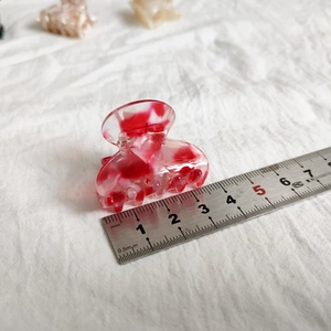 Detail showing a 4cm red and white marble texture small hair claw clip with measuring scale