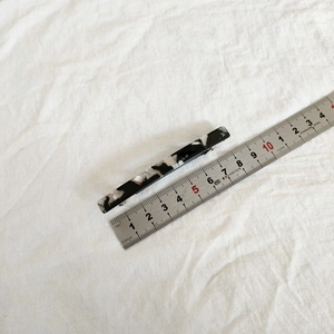 Detail view of a 6.5cm marble pattern acetate hair clip with a measuring ruler