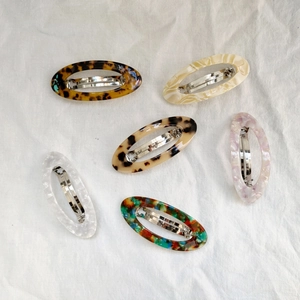 Lot de six barrettes ovales en acétate avec motifs écaille et marbre sur tissu blanc