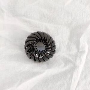 Detail view of a black bird nest hair clip showing retractable teeth and glossy resin finish