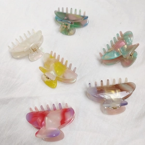 Set of six colorful marble pattern acetate hair claws on a white linen fabric background