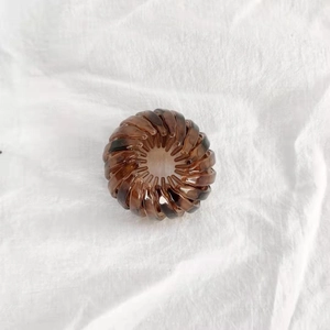 Top view of amber brown bird nest hair claw with resin spiral structure on white fabric