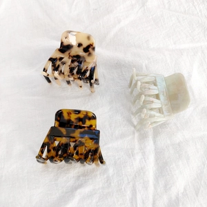 Detailed macro view of three tortoiseshell acetate hair claws on white linen fabric