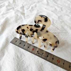 Detail view of a French leopard print acetate hair claw clip on white fabric background