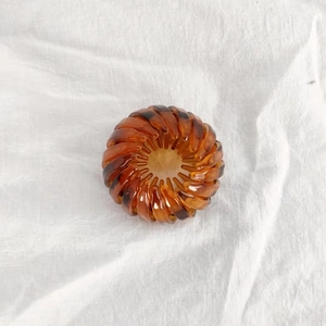 Close-up of expandable bird nest hair clip with amber leopard pattern on fabric