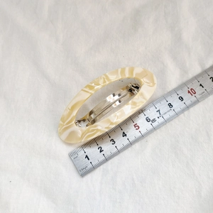 Vue détaillée d'une pince à cheveux crème de 7cm avec règle pour échelle de taille