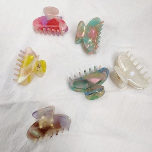 Detailed set of six marble texture acetate hair claws with gold springs on linen fabric