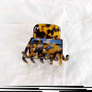 Detail of tortoise shell hair claw clip with leopard pattern on white linen fabric