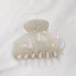 Detail of pearlescent white acetate hair claw clip with iridescent shell texture finish