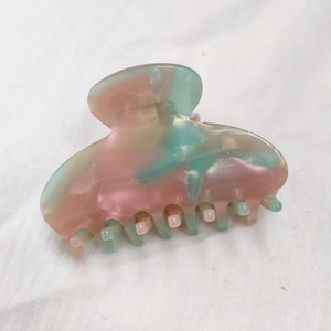 Macro detail of the iridescent pink and green marbled acetate hair claw clip texture