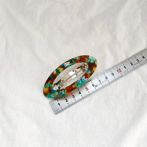 Détail d'une pince à cheveux ovale en acétate de 8,5cm avec texture marbrée