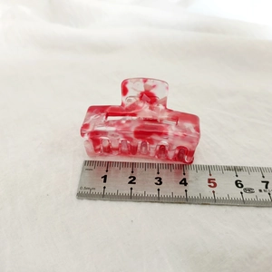 Détail d'une pince à cheveux en acétate marbré rouge et blanc de 4,2 cm avec échelle