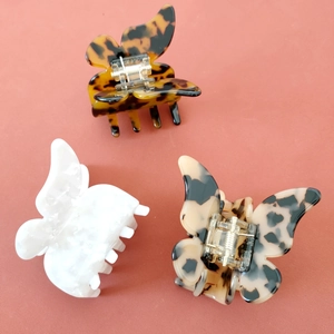 Trois pinces à cheveux papillon en acétate aux motifs écaille et perle sur fond rouge