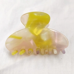 Close-up of yellow and pink acetate hair claw clip with glossy mosaic texture finish