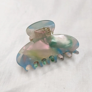 Macro detail of iridescent acetate hair claw clip showing pearlescent pastel gradients