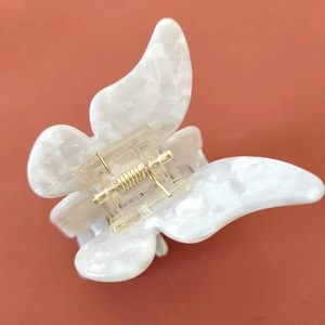 Vue détaillée de la pince à cheveux papillon en acétate avec texture perle marbrée