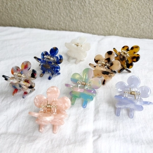 Close-up of small floral hair claws in various colors on white fabric texture