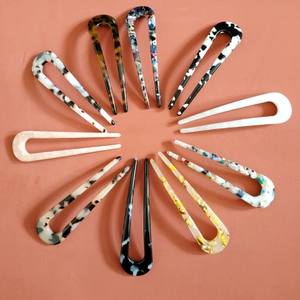 Flat lay of 12 colorful cellulose acetate U-shaped hair pins in various marbled patterns