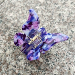 Détail de la pince à cheveux papillon en acétate marbré violet avec ressort doré