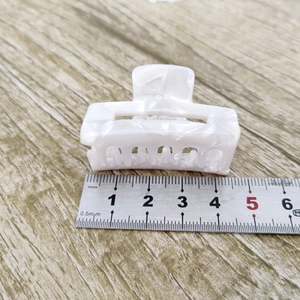 Vue détaillée d'une pince à cheveux de 4,5 cm en acétate marbré blanc sur bois
