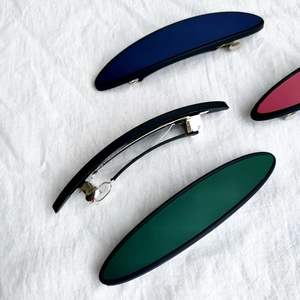 Minimalistische matte Haarspangen und Feder-Haarclips auf weißem Stoffhintergrund