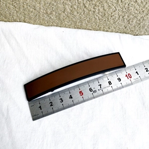 Détail d'une pince à cheveux mate marron foncé de 10,5 cm avec bordure noire sur tissu