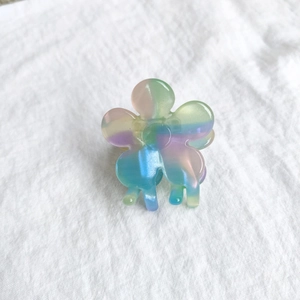 Detailed close-up of rainbow gradient flower hair claw clip with pearl luster finish