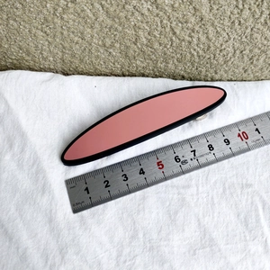 Detailansicht einer 10,5 cm mattrosa ovalen Haarspange mit schwarzen Rändern auf Stoff