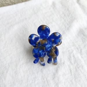 Macro shot of blue floral acetate hair claw clip on white fabric with marble pattern