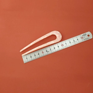 Detail showing pink marble acetic U-shaped hair pin measured with a ruler for size