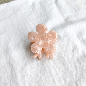 Detailed top view of a peach pink flower hair claw clip with marble texture on white fabric