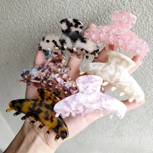 Detail view of 6-piece assorted acetate hair claw clips held in hand for women