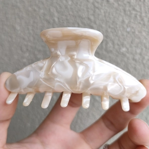 Detailed close-up of cream marble texture hair claw clip with smooth acrylic finish