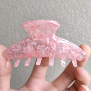 Detail of pink marble acetate hair claw clip showing glossy texture and resin material