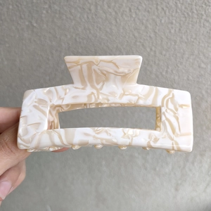 Detail showing marble texture acetate hair claw clip with rectangular design for thick hair