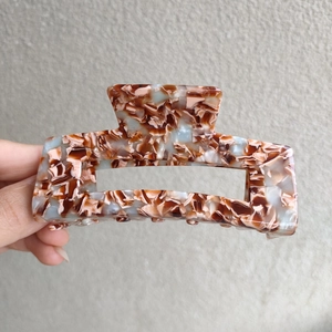 Detailed close-up of a large 10cm square acetate hair claw with brown marble leopard pattern