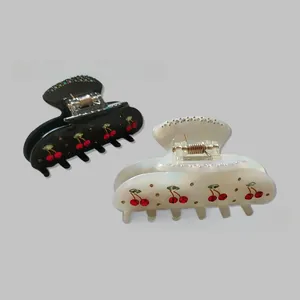 Detail view of black and pearly white cherry hair claws with sparkling rhinestones set