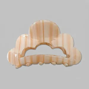 Détail d'une grande pince à cheveux en forme de nuage avec motif à rayures marron et crème