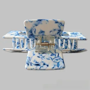 Macro detail of 10cm blue and white marbled hair claw clip with gold metal spring