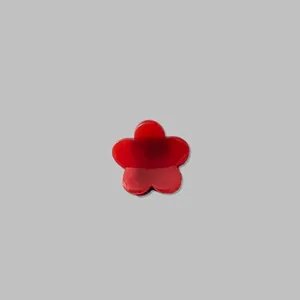 Détail d'une mini pince à cheveux en forme de petite fleur rouge à finition brillante