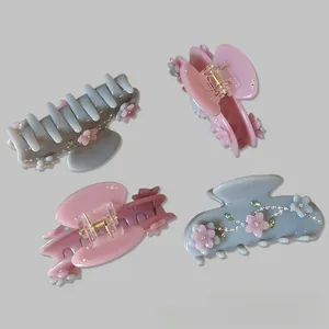 Detail of four floral hair claws with rhinestones in grey-blue and light pink sets