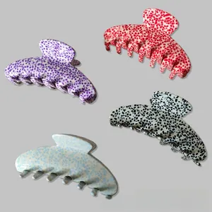 Detail of four large hair claws with colorful stone patterns and glossy finish