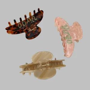Three-piece hair claw set with tortoiseshell and marble patterns featuring rhinestone lettering