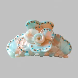 Detail view of flower hair claw clip with mint green acetate and sparkling rhinestones
