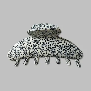 Macro shot of large black and white cow print hair claw clip with polished finish