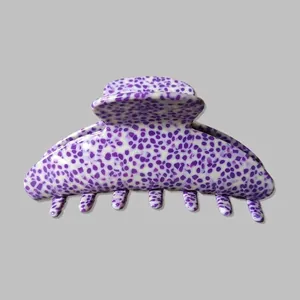 Detailed macro view of large white acetate hair claw clip with purple speckled pattern