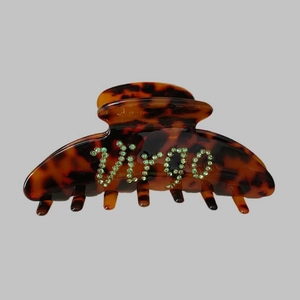 Detailed close-up of Virgo logo with green rhinestones on tortoise shell hair claw clip