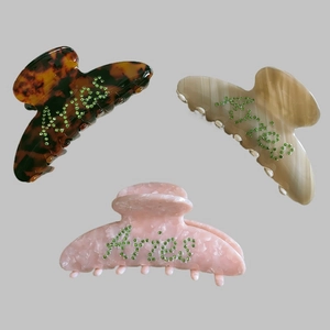 Three Aries rhinestone acetate hair claws in tortoise, beige, and pink marble patterns